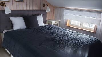 Un dormitorio con una cama grande, dos lámparas de noche, una mesita de noche y una ventana con cortinas.