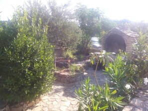 A stone pathway leading to a rustic stone structure, surrounded by lush greenery and flowering plants. - Sunny Pool Apartments - One Bedroom Apartment With Sea View (Jasenice)
