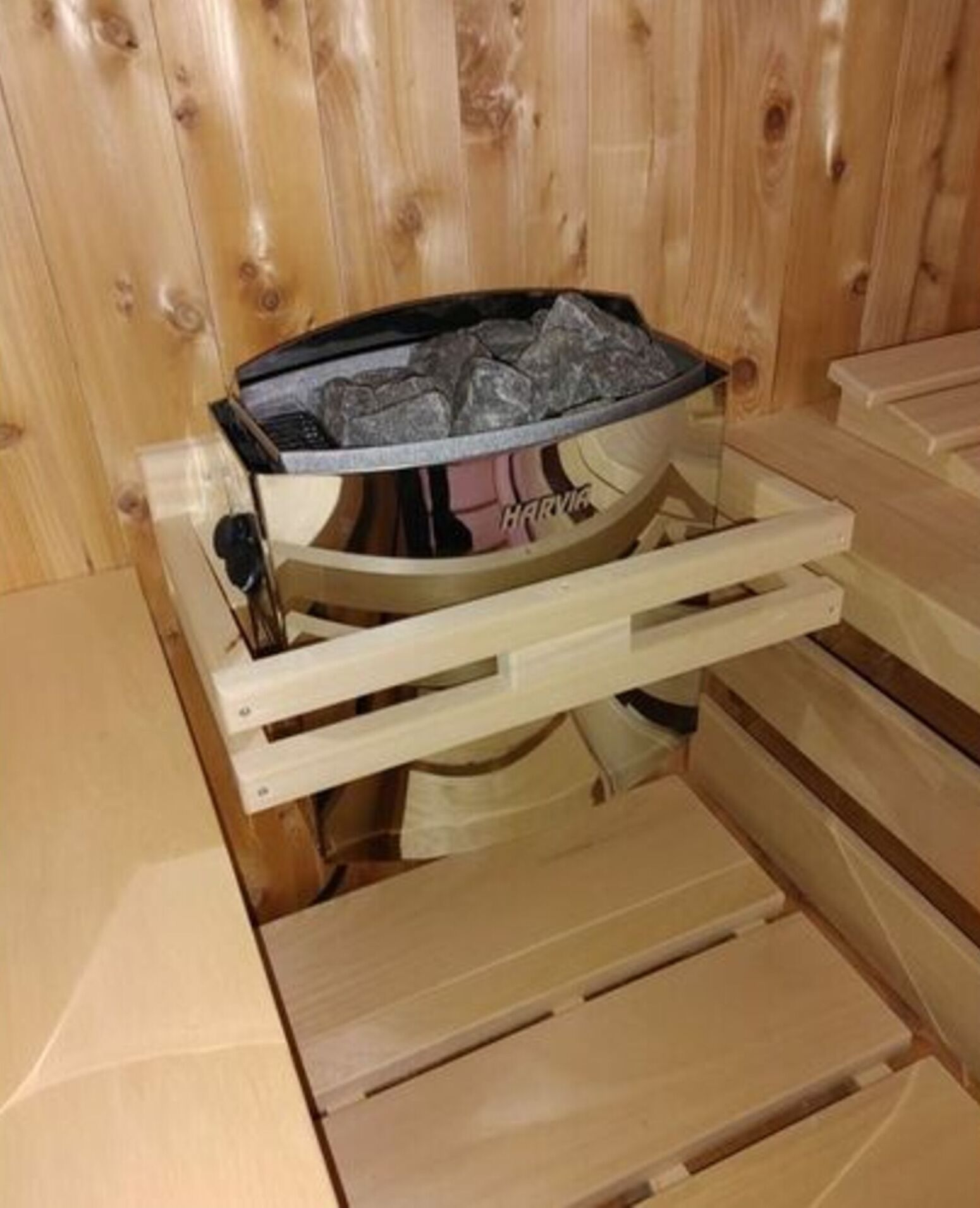 Una sauna con interior de madera y el nombre de la marca 'HARMAN' a la vista.