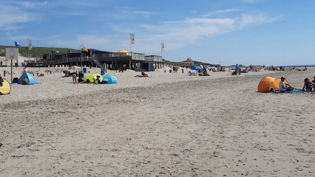 Una playa con tiendas de campaña y un muelle.