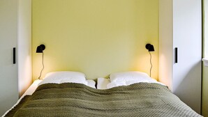 A room with a bed, two wall-mounted lamps, and a wardrobe. - 4 Person Holiday Home in Ronne (Ronne)