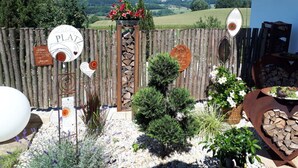 A rustic outdoor setting with a wooden fence, decorative signs, and a view of a mountainous landscape. - Attractive Apartment in Bavaria (Schoellnach)