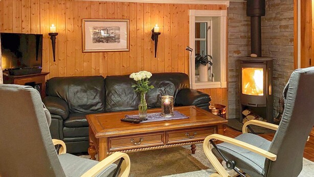 Ein gemütliches Wohnzimmer mit Kamin, Ledersofa, Couchtisch aus Holz und Fernseher.