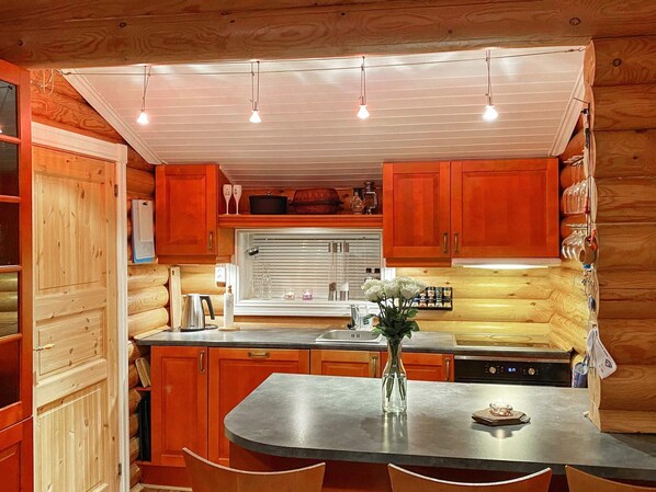 A compact kitchen with wooden cabinets, a central island, and pendant lighting.