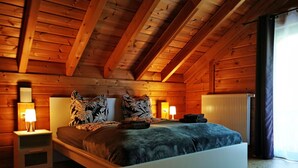 Quarto de cabana de madeira com uma cama, duas mesas de cabeceira e um radiador.