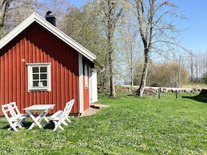 A red wooden house with a white door and window, a small table, and two white chairs in front. - 4 Person Holiday Home in Falkoping (Falkoping)