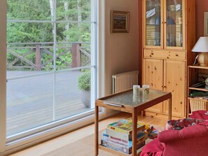 A room with a large window, a wooden cabinet, and a table with books.