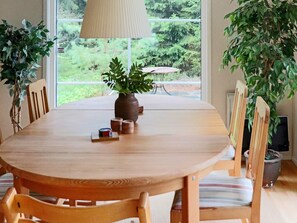 A dining table with chairs, a vase with a plant, and a lamp. - 4 Person Holiday Home in Fjaras (Fjärås)