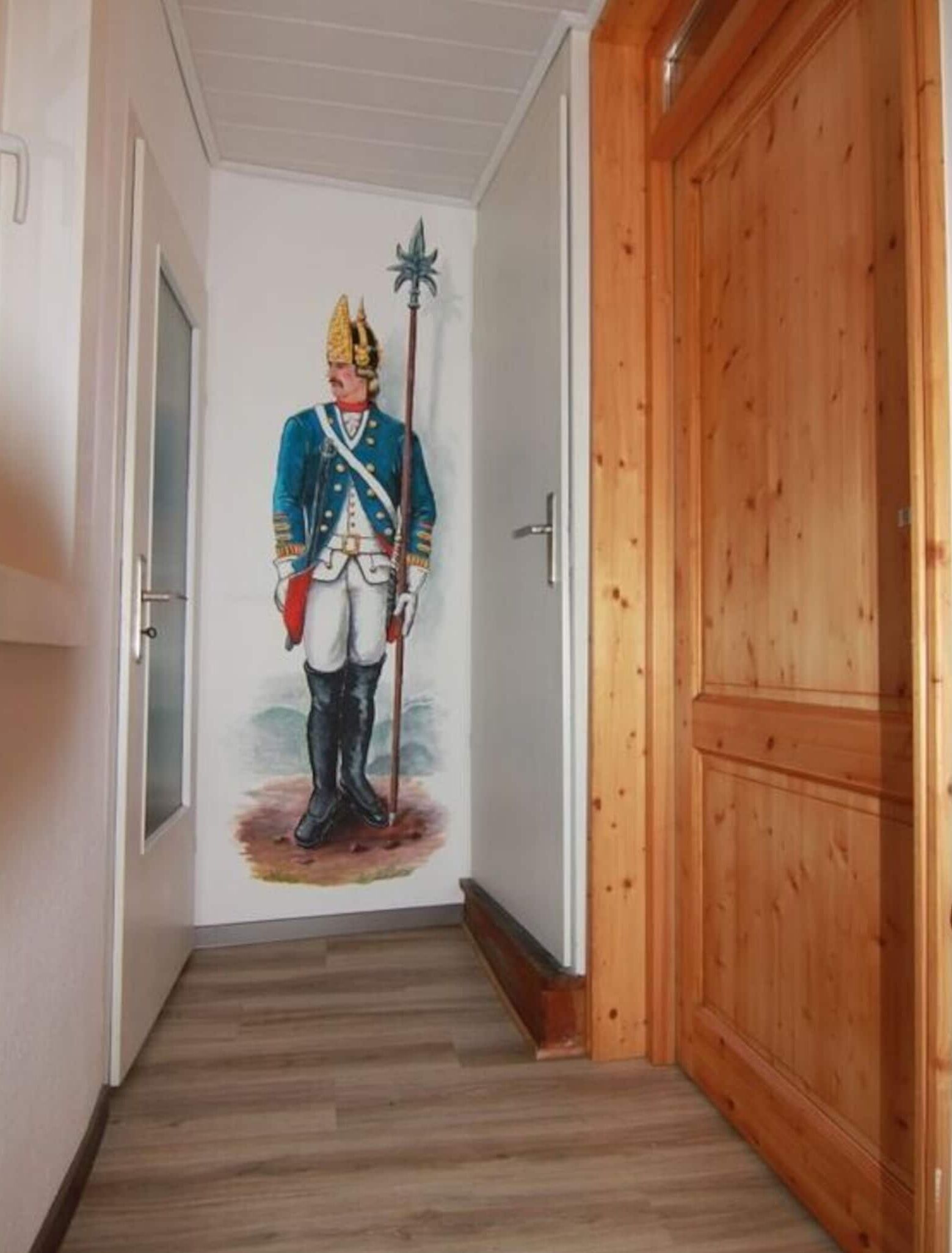 A hallway with a wooden door and a mural of a figure in military uniform.