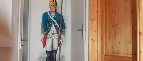 A hallway with a wooden door and a mural of a figure in military uniform.