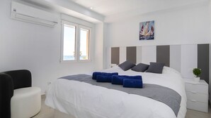Una camera da letto moderna con un letto grande, un tavolino con una pianta e una finestra vista palme.
