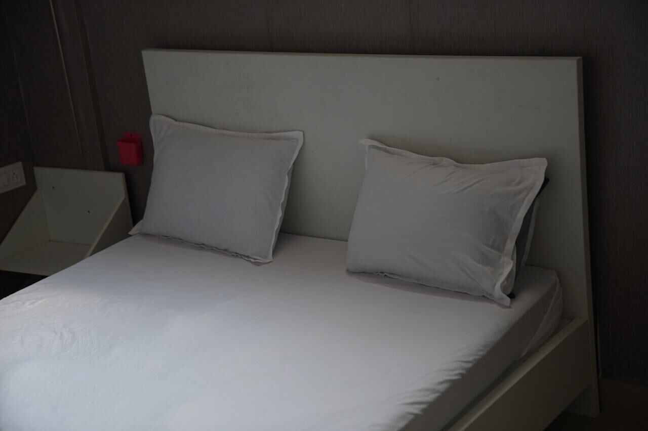 A bed with a white headboard and two pillows.