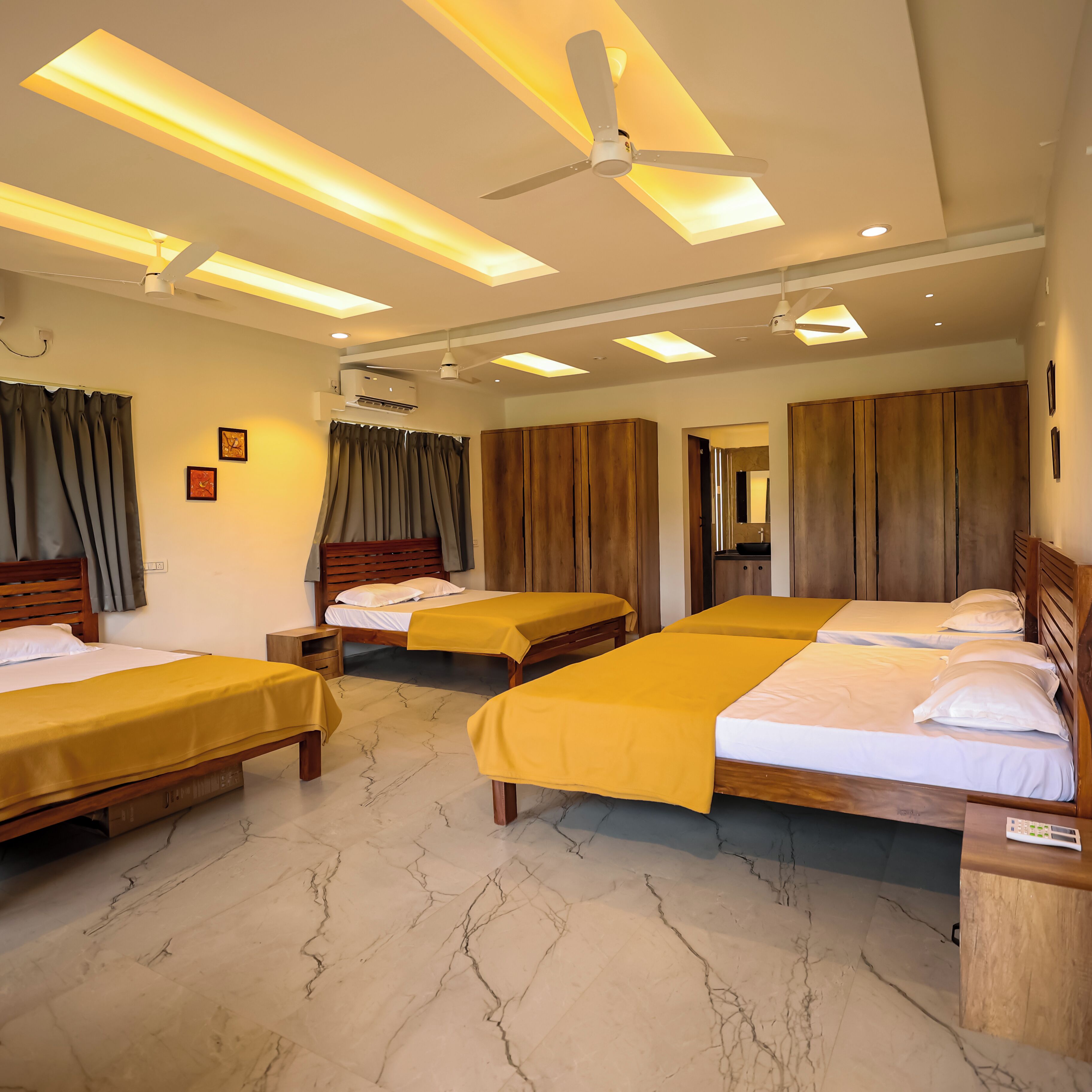 A hotel room with three beds, a ceiling fan, recessed lighting, and a marble floor.