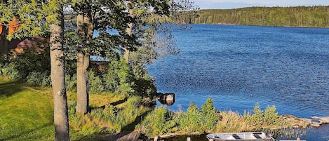 A lakeside property with a wooden dock, outdoor seating, and a view of the lake.