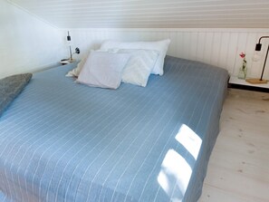 A bedroom with a bed, pillows, a nightstand, a lamp, and a small table with a vase. - 4 Star Holiday Home in Hova (Hova)