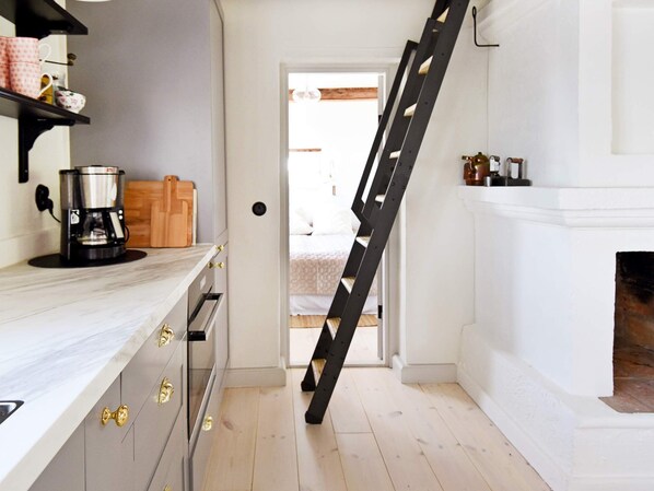 A kitchen with a coffee maker, a wooden cutting board, and a ladder leaning against the wall.