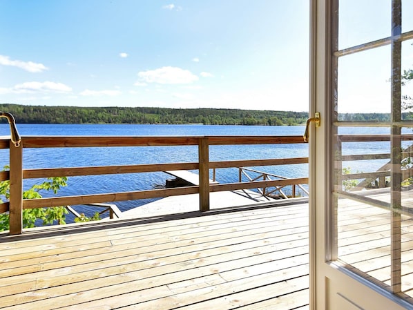 Une terrasse en bois offrant une vue sur un lac et une forêt.