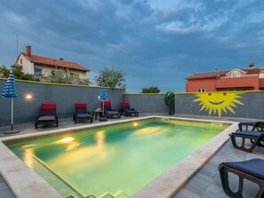 An outdoor swimming pool with lounge chairs and umbrellas, surrounded by a low wall and houses. - Sunce Comfortable Holiday Residence (Pula)