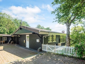 A small, single-story building with a green exterior and a white picket fence. - 6 Person Holiday Home in Haderslev (Haderslev)