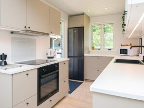Una cocina moderna con horno empotrado, refrigerador de acero inoxidable y microondas en la encimera.