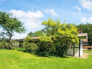 A house with a green lawn, a tree, and a small shed.