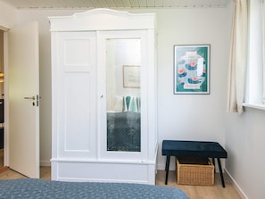 A room with a white wardrobe, a framed picture on the wall, a bench, and a wicker basket. - 6 Person Holiday Home in Haderslev (Haderslev)