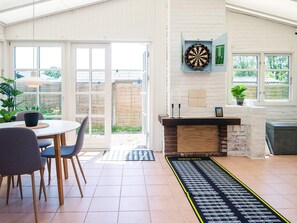 A dining area with a table and chairs, a dartboard, and a check-out sign on the floor.