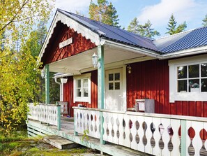 A red wooden house with a white porch and a blue roof.