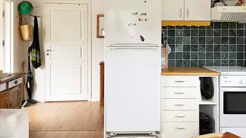 A kitchen with a white refrigerator, wooden cabinets, a wooden countertop, and a hanging basket.