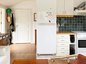A kitchen with a white refrigerator, wooden cabinets, a wooden countertop, and a hanging basket.