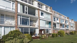 Une rangée de maisons mitoyennes dotées de balcons, de grandes fenêtres et d’une pelouse bien entretenue.