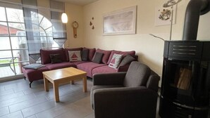 A living room with a sectional sofa, a coffee table, a fireplace, and a large window. - Holiday Home Windfluchter (Graal Mueritz)