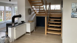 A modern loft bedroom with a wooden staircase, built-in desk, and a large window. - Holiday Home With Garden Terrace Near Baltic Sea (Wendtorf)