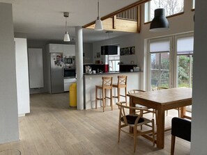 Enjoy meals in this well-lit kitchen with a dining area, featuring a refrigerator, oven, and microwave, and a large window with a view.