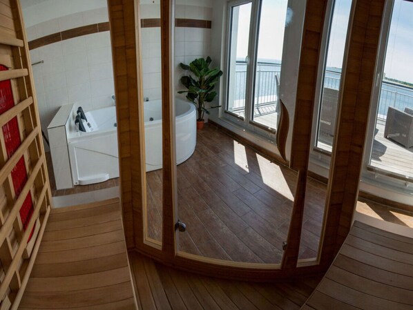 Un baño con bañera, lavamanos y una planta en maceta.