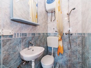 Une salle de bain équipée d’un lavabo, de toilettes, d’une douche et d’un porte-serviettes.