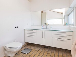 Ein modernes Badezimmer mit Toilette, Glaswaschbecken und Fliesenboden.
