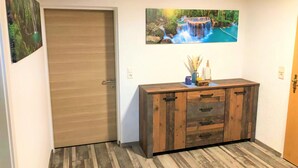 A hallway with a wooden door, a wooden cabinet with drawers, and two framed pictures on the wall. - Tranquil Apartment in Polling With Terrace (Straßburg)