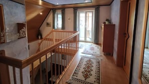 Un hall d’entrée spacieux avec un plancher en bois, un escalier en bois et une grande verrière.
