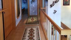 Un couloir avec des portes en bois, un tapis à motifs et une rambarde en bois.