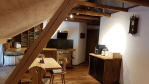 Une cuisine chaleureuse avec un plancher en bois, une table à manger et des chaises. On y trouve également un téléviseur, une machine à café et des placards.