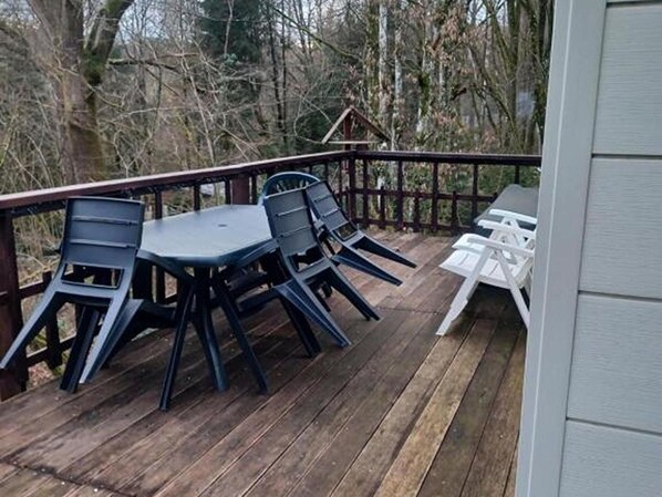 Eine Holzterrasse mit Tisch und Stühlen, umgeben von einem Hollerker.