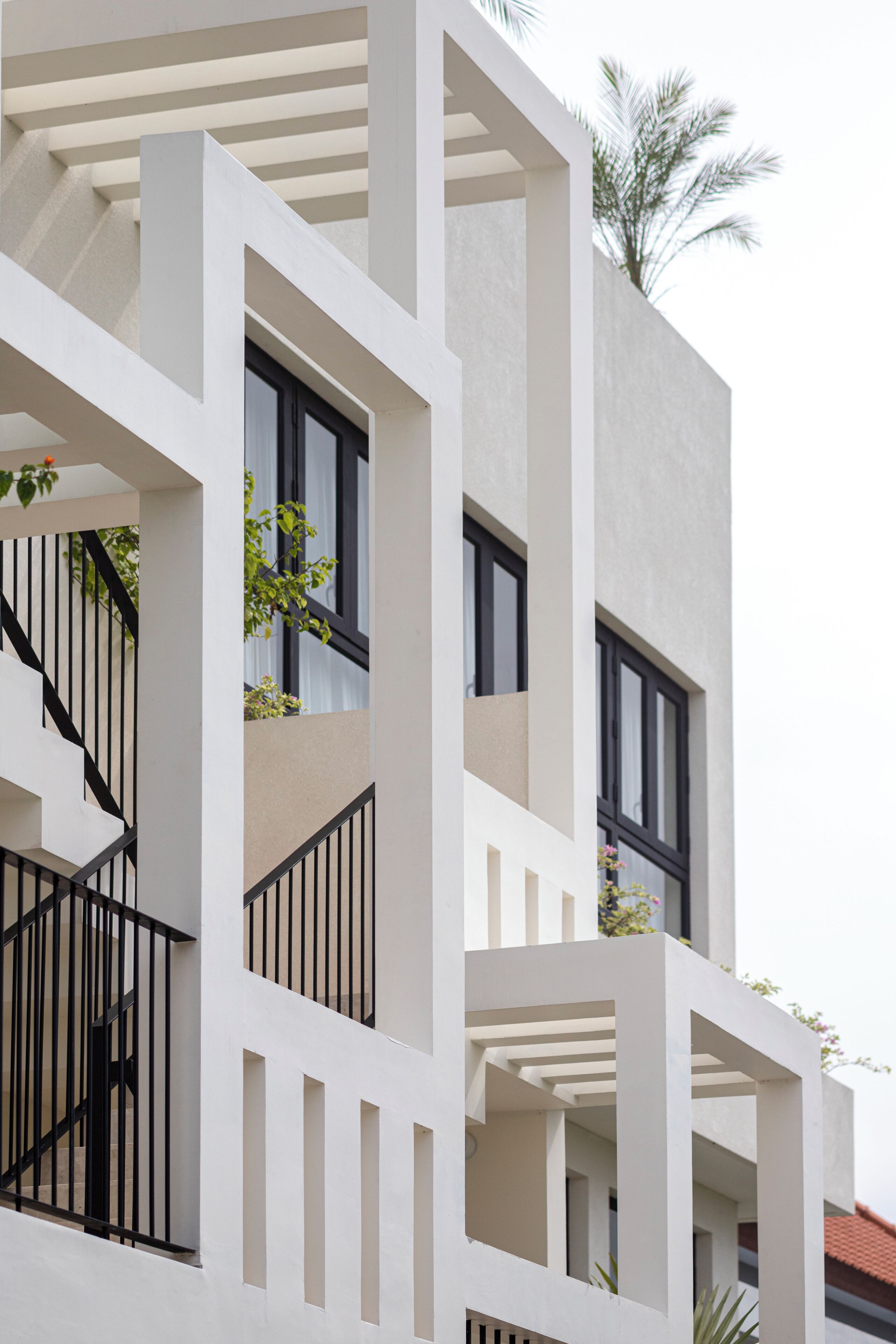 A modern building with a white facade, multiple balconies, and black railings.