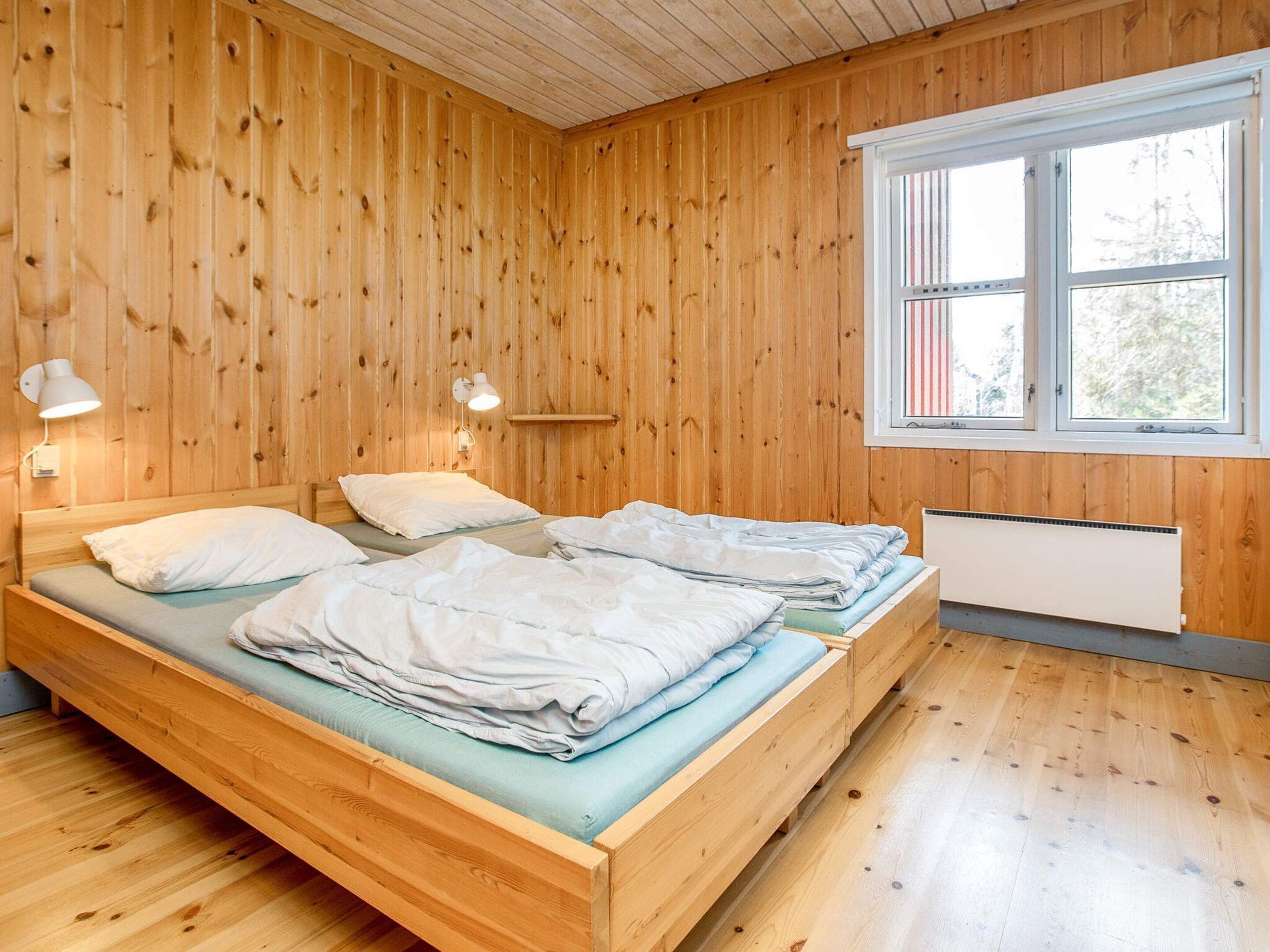 Una habitación con paneles de madera, dos camas, un ventanal y un radiador.
