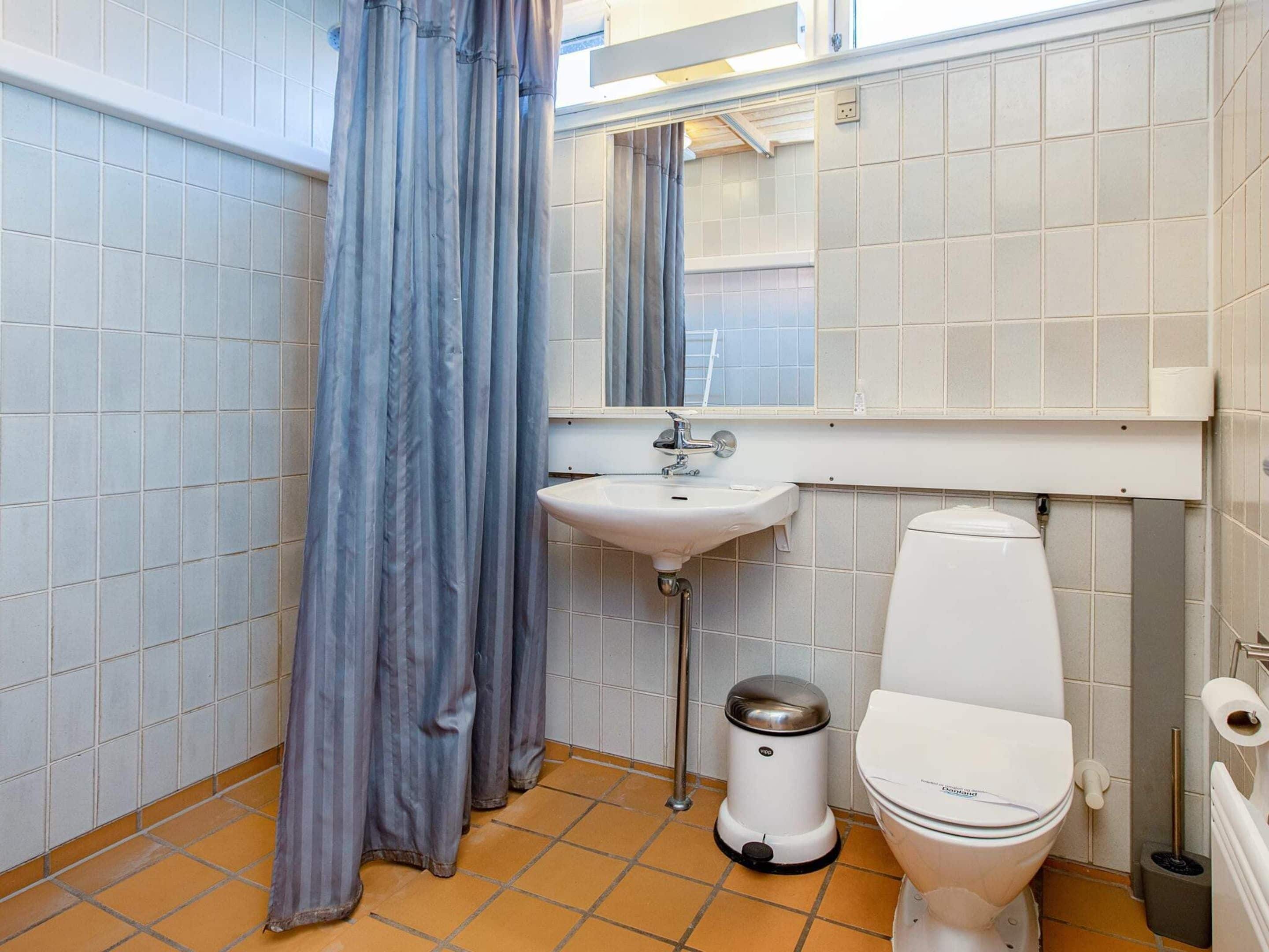 A bathroom with a toilet, sink, and trash bin.