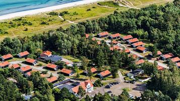 An aerial view of a residential area with houses, a beach, and a forested area.