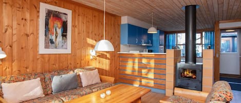 A cozy wooden interior with a sofa, a wooden table, and a fireplace.