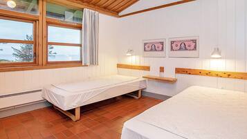Habitación con dos camas, cabeceros de madera, una ventana con cortinas y billetes enmarcados en la pared.