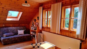 A cozy wooden cabin with a loft bed, a sofa, a small table, and a bookshelf. - Alpine Hut in Murau Near Ski Slope (Sankt Georgen am Kreischberg)