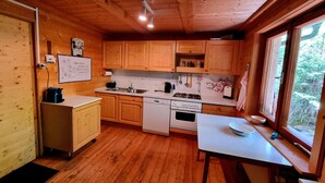 A wooden cabin kitchen with a stove, sink, and wooden cabinets. - Alpine Hut in Murau Near Ski Slope (Sankt Georgen am Kreischberg)